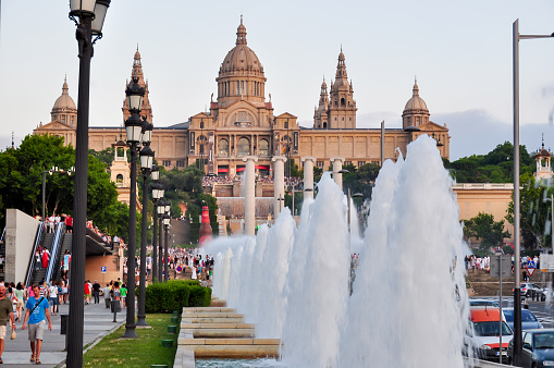 Barcelona, Spain - July 02, 2019: National Palace (Palau Nacional) building on top of Montjuic hill and magic fountains show at sunset in Barcelona