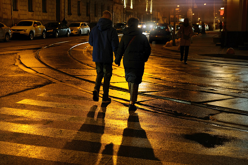 People walking along the pedestrian crossing, night city streets. Nightlife, lifestyle.