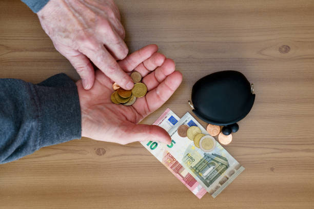 руки подсчитывают маленькие монеты. на столе бумажник и евро. - маленькая группа объектов стоковые фото и изображения