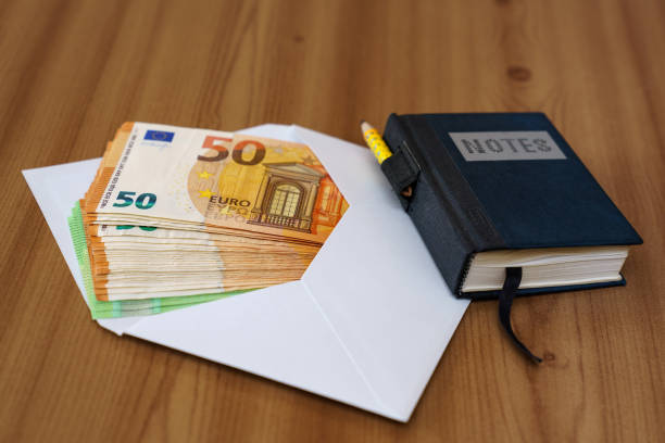 istock Envelope with fifty and one hundred Euro banknotes on the table next to a notebook. 1311523552