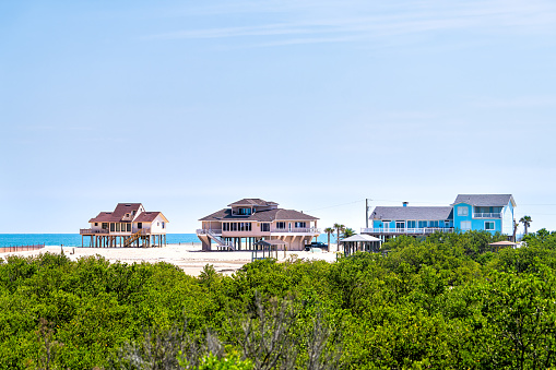 Colorful stilted vacation houses on stilts at oceanfront waterfront of Atlantic ocean beach by mangrove forest in summer at Palm Coast, Florida