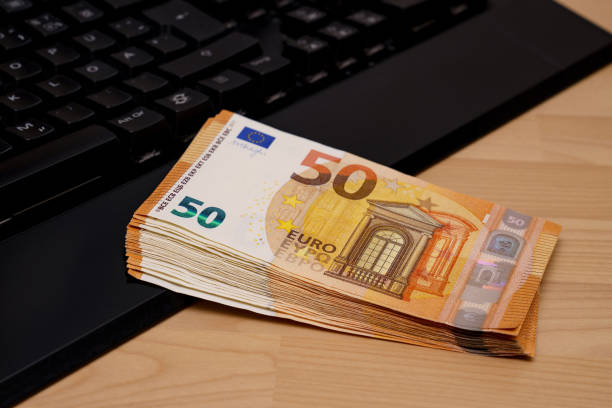 un paquete de cincuenta billetes de euro en un teclado de ordenador. - euro symbol currency internet computer keyboard fotografías e imágenes de stock