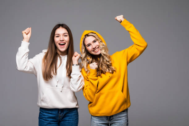 istock Two young women doing winner gesture celebrating isolated on gray background 1311527620