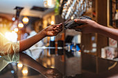Woman paying with mobile phone at bar