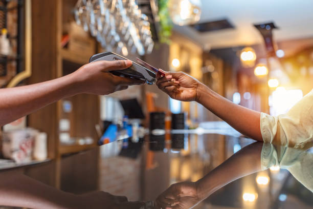 Point of sale is a breeze Young African Woman paying by credit card in a coffee shop. paid stock pictures, royalty-free photos & images