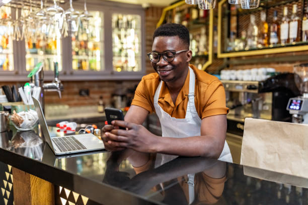 um empreendedor ocupado precisa se manter conectado - owner small business restaurant african ethnicity - fotografias e filmes do acervo