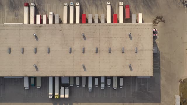 Aerial view of goods warehouse. Logistics center in industrial city zone from above. Aerial view of trucks loading at logistic center