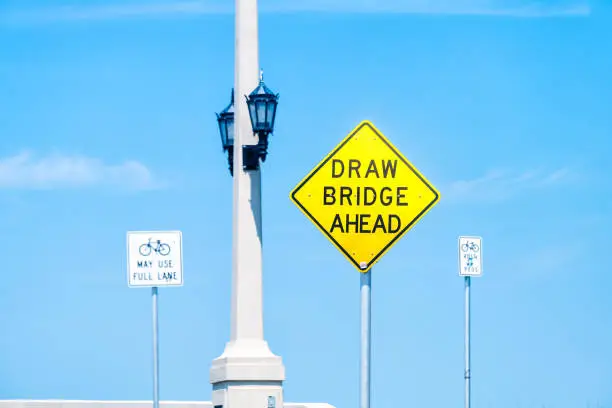Draw drawbridge yellow road traffic sign at Bridge of Lions bascule bridge at St. Augustine, Florida from Anastasia island isolated against blue sky in summer