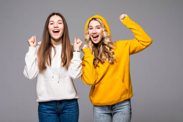 istock Two young women doing winner gesture celebrating on gray background 1311528912