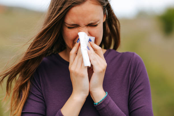 istock Woman with allergy symptom blowing nose in nature 1311530607