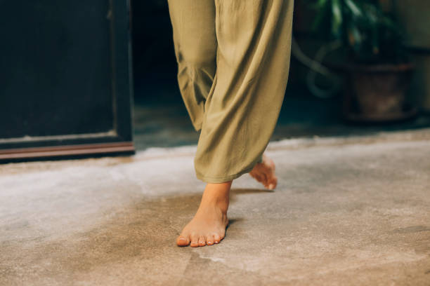 An unrecognizable woman dressed in green sirwal pants, walking barefoot