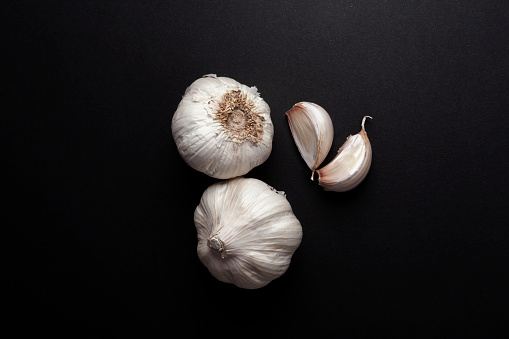 still life of garlic heads and garlic cloves on black background.  healthy ingredients food concept.