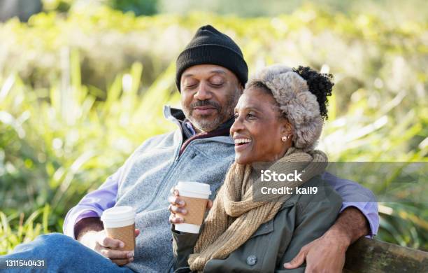 African-American relaxing on park bench drinking coffee
