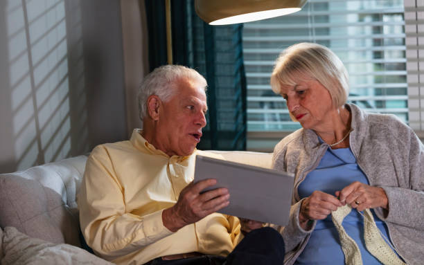 istock Senior couple on sofa talking, looking at digital tablet 1311544366