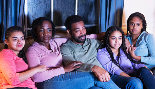 istock African-American family with three daughters watching TV 1311544809