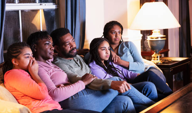 African-American family with three daughters watching TV