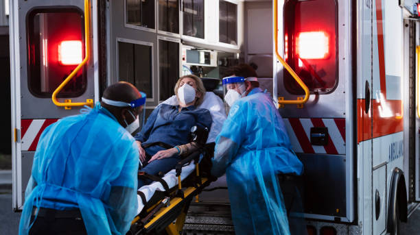 istock Paramedics loading patient into ambulance, wearing PPE 1311546994