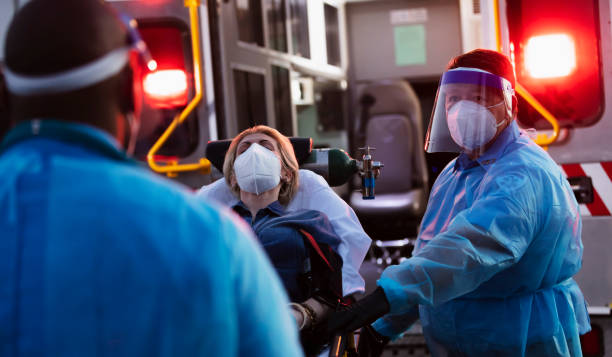 istock Paramedics loading patient into ambulance, wearing PPE 1311547012