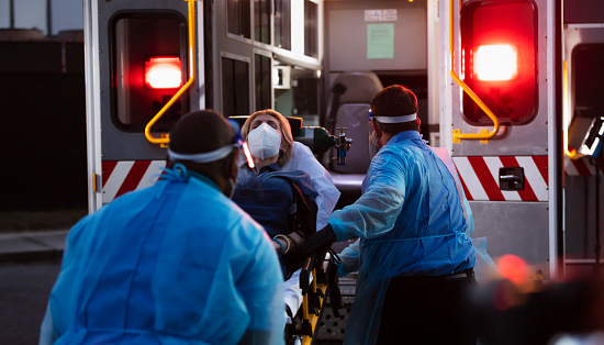 Paramédicos cargan a paciente en ambulancia, con EBP photo