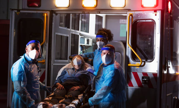 istock Paramedics loading patient into ambulance, wearing PPE 1311547026