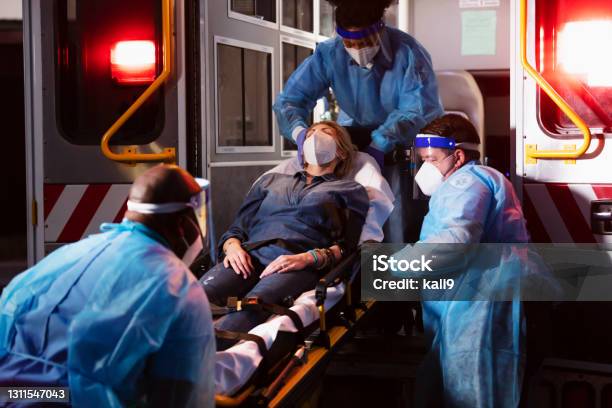 Paramedics Loading Patient Into Ambulance Wearing Ppe Stock Photo - Download Image Now