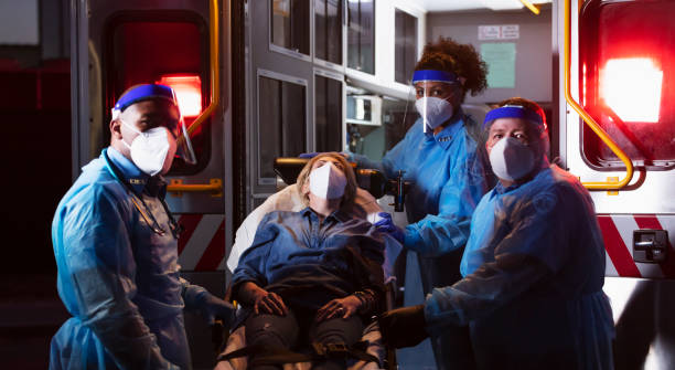 istock Paramedics loading patient into ambulance, wearing PPE 1311547560