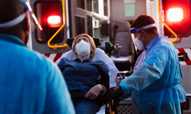 istock Paramedics loading patient into ambulance, wearing PPE 1311547572