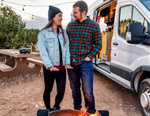 istock Young Multi-Ethnic Couple Out Camping, Warming Themselves By The Campfire, Talking An Enjoying The Evening 1311552961