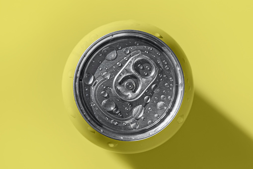 Yellow pop can with water drops casting shadow on yellow background