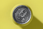 Yellow pop can with water drops casting shadow on yellow background