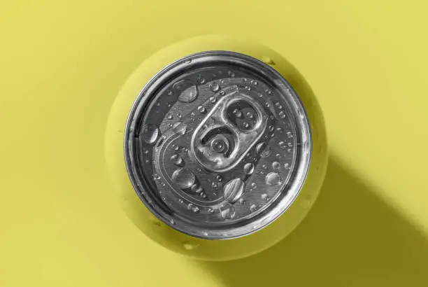 Photo of Yellow pop can with water drops casting shadow on yellow background