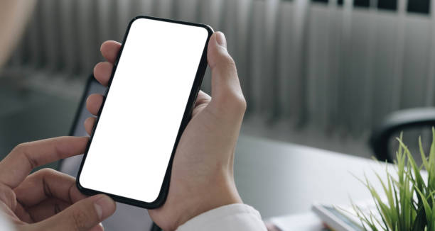 istock Mockup image of hand holding mobile phone with blank white screen in home 1311557900