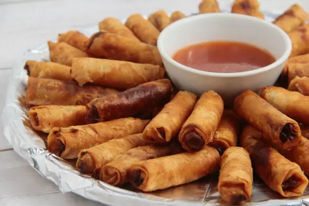 Photo of freshly cooked Filipino food called Lumpiang Shanghai or fried ground pork meat in spring roll wrapper.