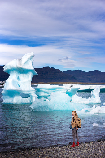Glacier Lagoon, Iceland: A woman stands at the waterfront at Glacier Lagoon.