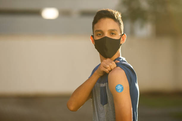 Boy showing his covid 19 vaccine badge Covid 19 vaccination vacina stock pictures, royalty-free photos & images