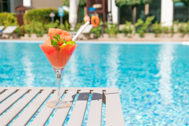 cóctel rojo fresco con hielo en copa en la piscina. jugo tropical en vacaciones de lujo. concept vacaciones de verano y viajes. - al lado de la piscina fotografías e imágenes de stock