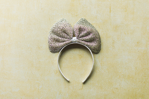 Directly above shot of a headband with a glittery bow on a yellow background.