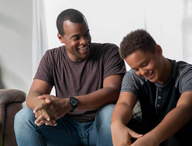 father gives life advice to his young teenage son at home - teenager parent father son imagens e fotografias de stock