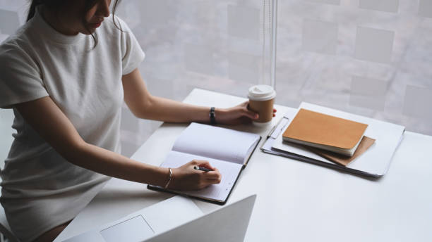 istock Businesswoman sitting in modern workplace and writing something on her notebook. 1311575156
