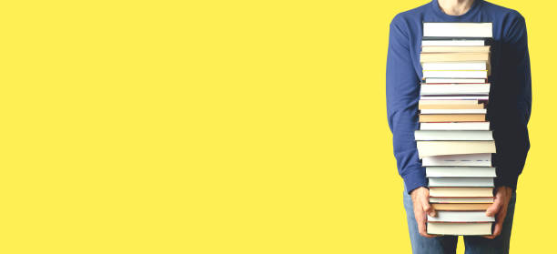 istock Student with books on a blank colored banner background. Education, reading and study background concept 1311582019