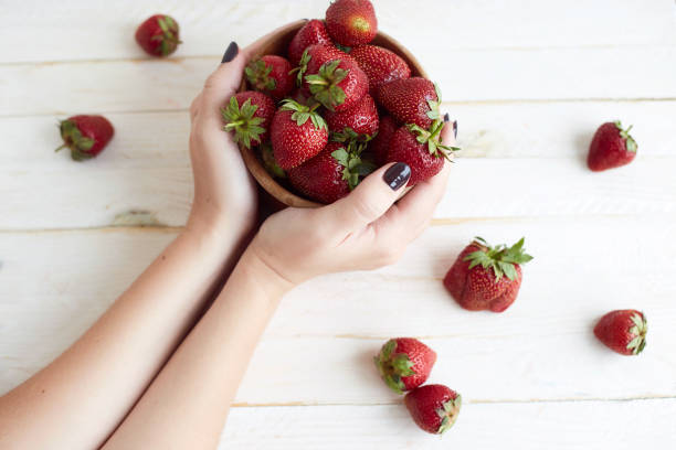 istock Fresh strawberries in woman hands. Harvest. Light rustic background. Organic berries. Space for text 1311587796