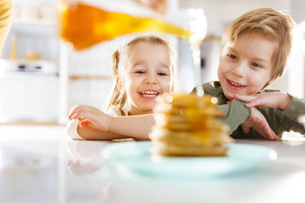 Small boy eating a huge stack of pancakes.