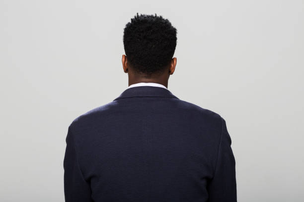 Rear view of man standing against grey background.