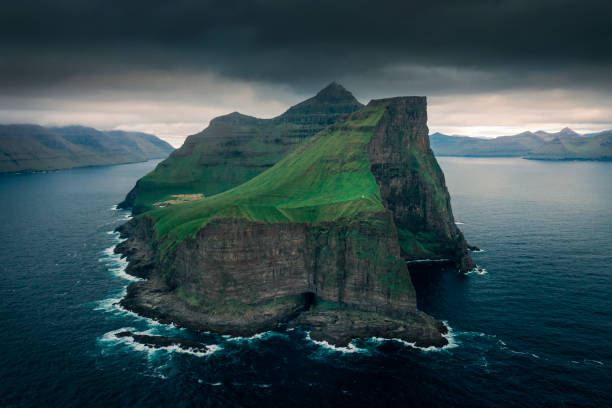 Steep cliffs of green Faroese island Kalsoy, from above, dark clouds in sky, Faroe Islands