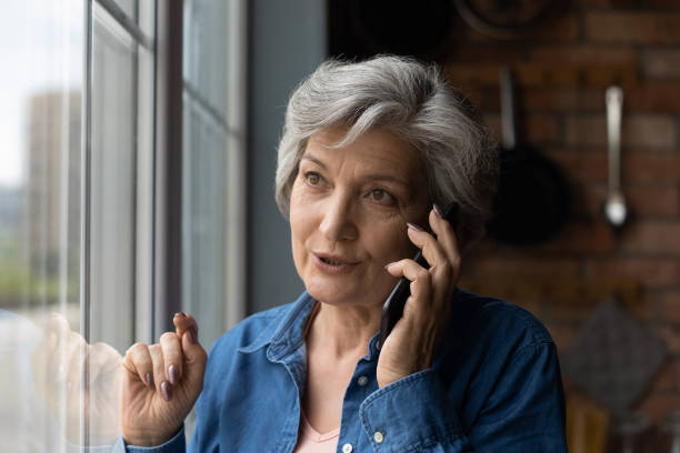 счастливая испаноязычная женщина-пенсионерка занимается приятным разговором по телефону - women telephone senior adult on the phone стоковые фото и изображения