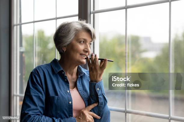 Confident Aged Hispanic Female Hold Modern Smartphone Dictate Audio Message Stock Photo - Download Image Now