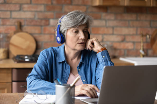 istock Active latin female retiree in headset confer online using laptop 1311594971