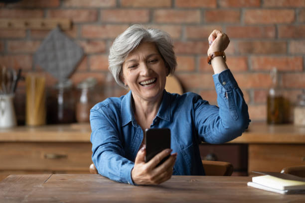 la grand-mère latine âgée ravie crier célèbrent gagner le jeu de téléphone portable - grandmother women one person senior adult photos et images de collection