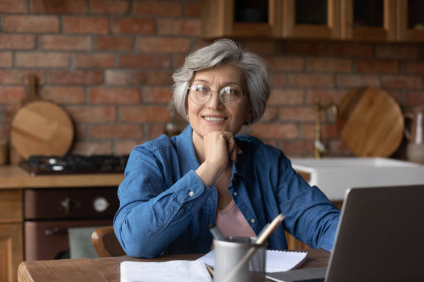 istock Dreamy aged lady study from home use laptop smile imagine 1311594980