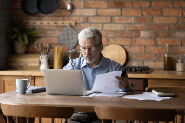 istock Thoughtful serious senior man provide mortgage payment online on pc 1311594981